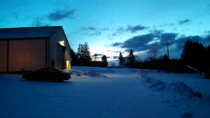 Cold, early sunrise with snow on the ground and dimly lit maintenance garage.